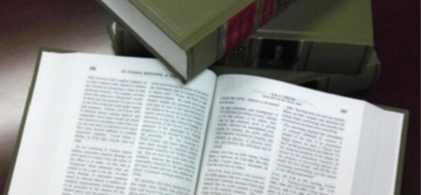 An open lawbook with a closed lawbook touching the top corner of the left open page.