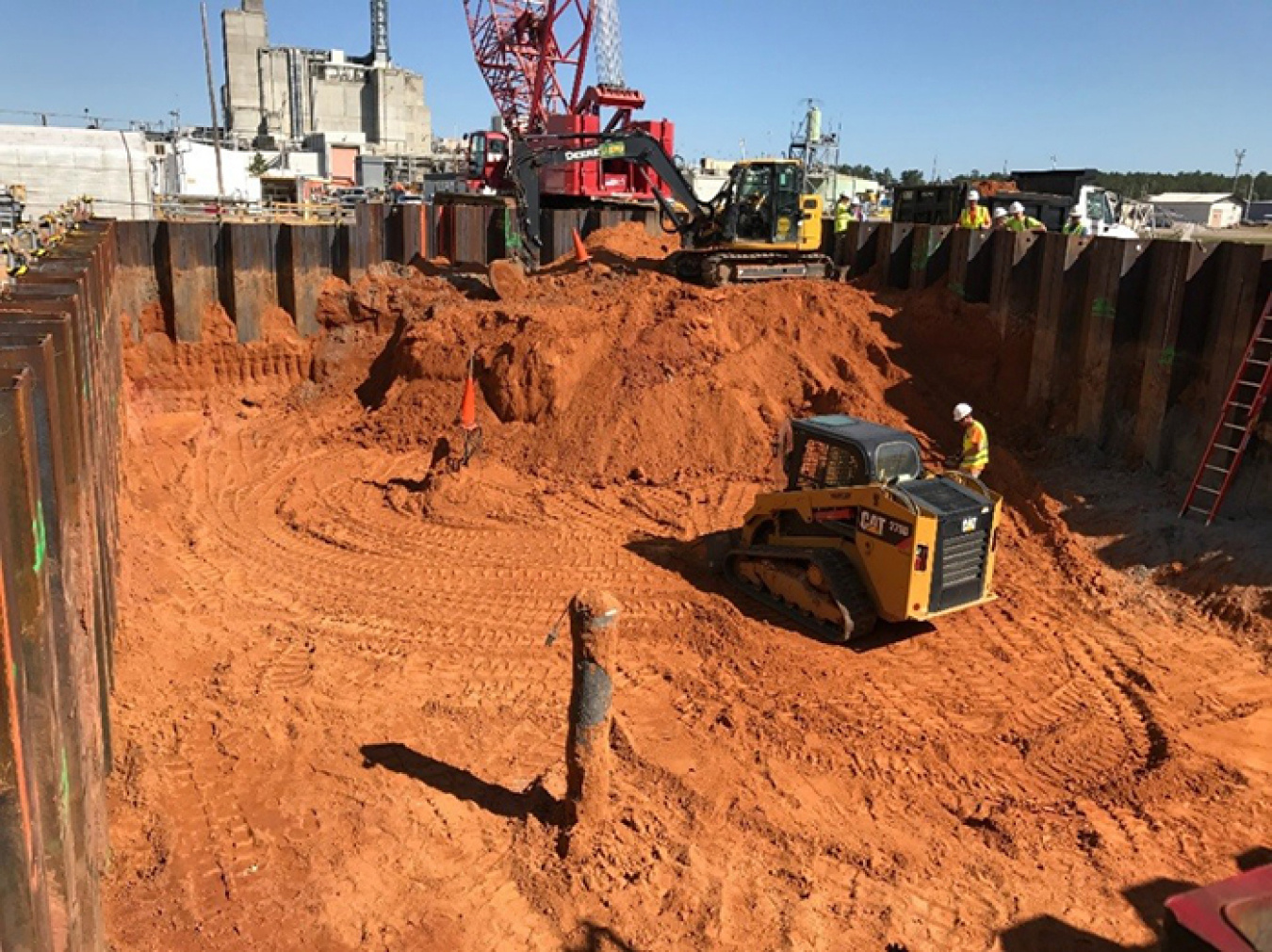 Workers excavate land to expose liquid waste transfer lines.