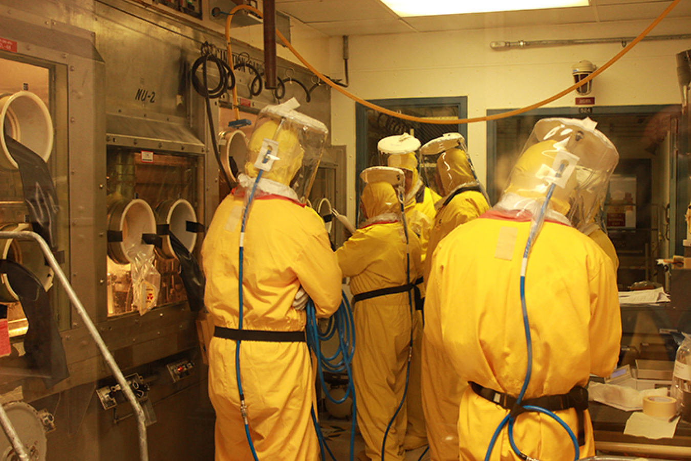 Employees work in an HB Line glovebox.
