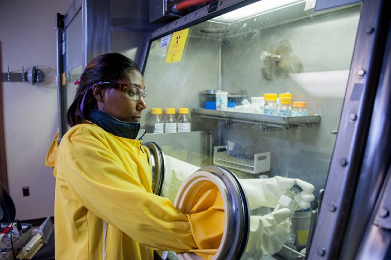 SRNS employee wears protective equipment to safely complete work inside a glovebox in the Savannah River Site F and H Area Laboratory.