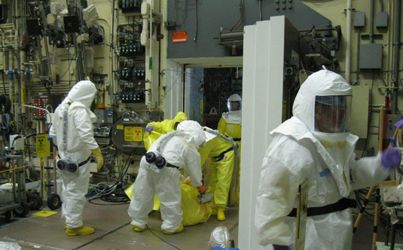 Workers remove and survey a bag of waste from the 324 Building airlock.