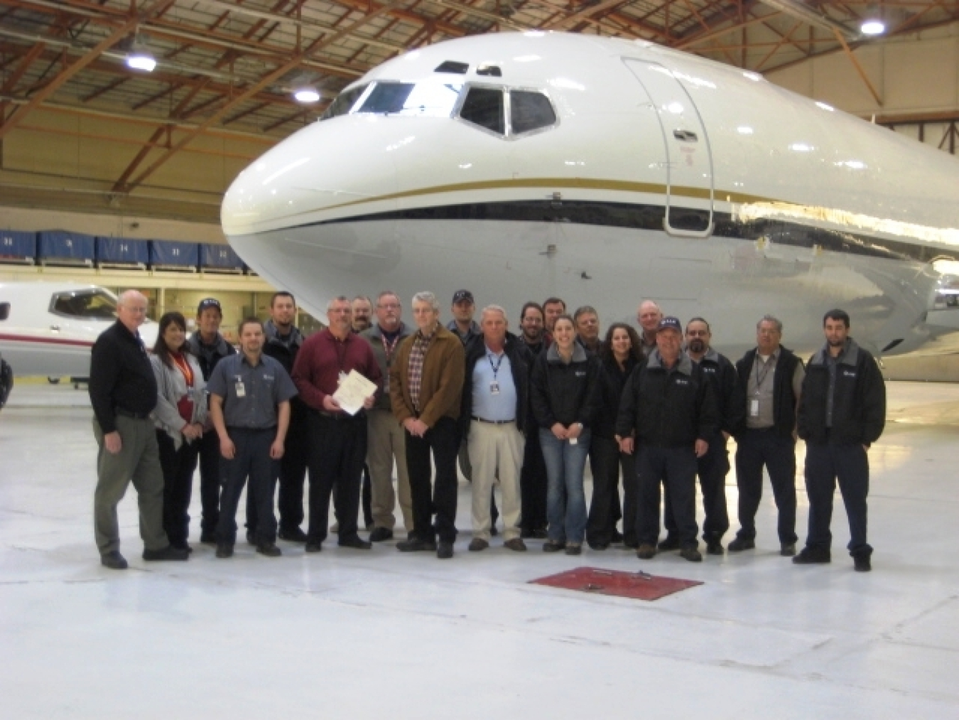 An airplane image with the group of people in front depicting aviation management