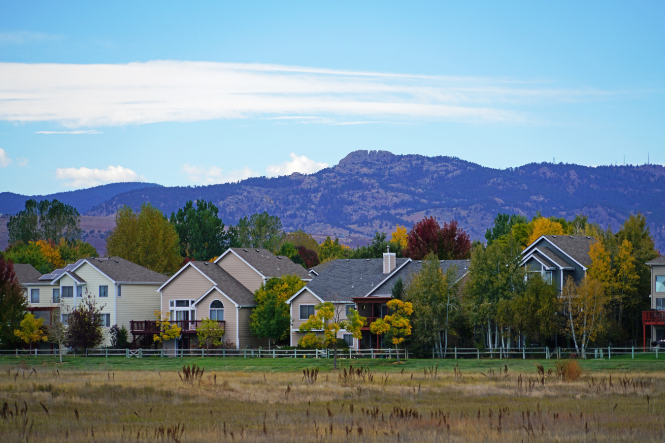 Photo of a row of houses with mountains rising beyond.