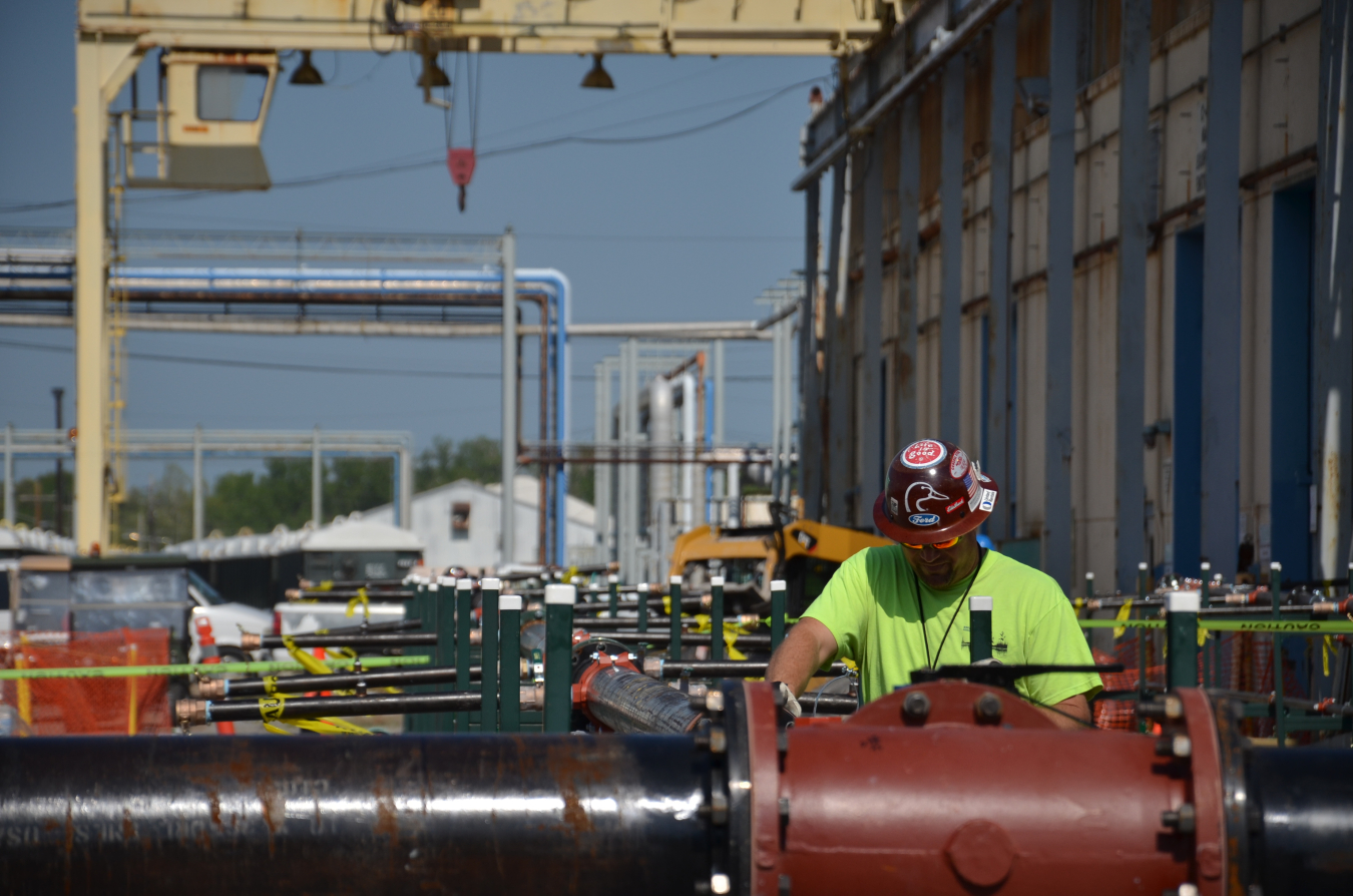 A photograph of a worker inspecting pipes leading to the above-ground treatment unit that was part of the C-400 Electrical Resistance Heating project to remove trichloroethene (TCE) from the groundwater near the Paducah Site's C-400 Cleaning Building.