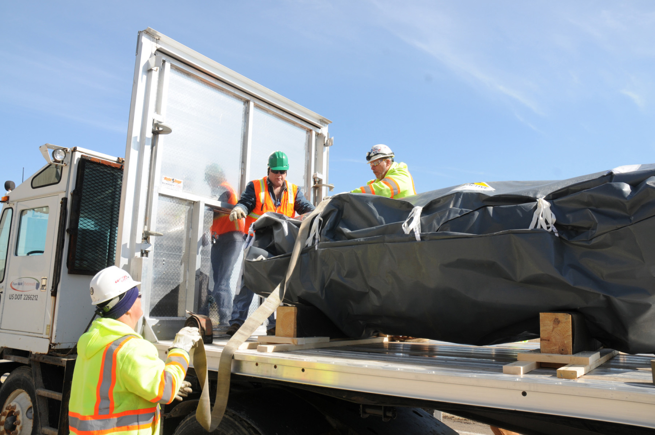 A photo of a tractor-trailer with a large, wrapped piece of process gas equipment (PGE) being prepared to ship off-site for disposition