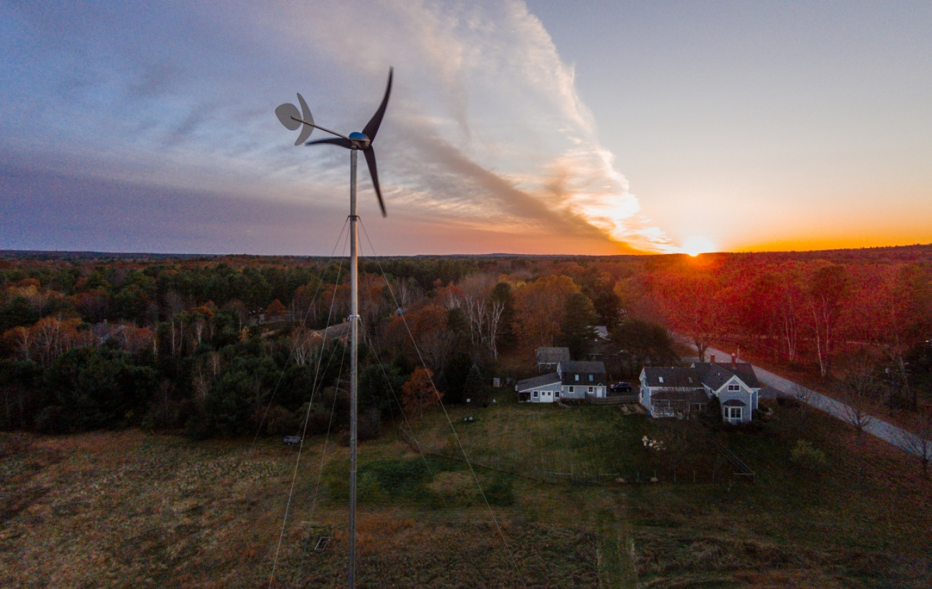Distributed wind turbine overlooking a home at sunrise.