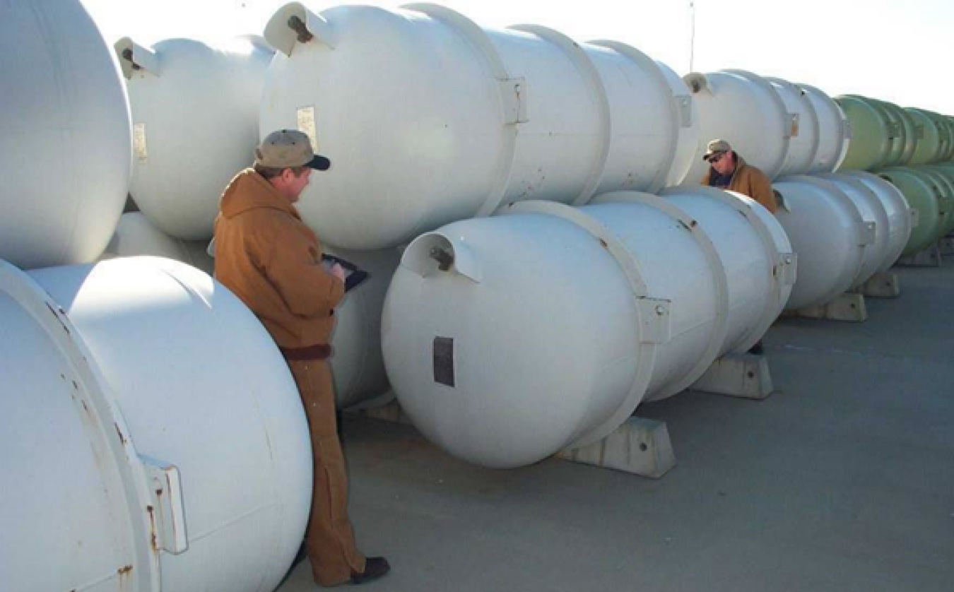 Workers inspect one of the thousands of specially designed storage cylinders that hold DOE's inventory of more than 740,000 metric tons of depleted uranium hexafluoride (DUF6).