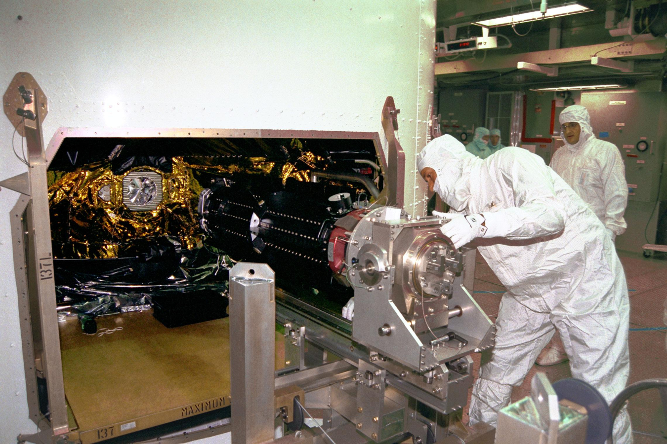 At Launch Complex 40 on Cape Canaveral Air Station, workers are installing three Radioisotope Thermoelectric Generators (RTGs) on the Cassini spacecraft.
