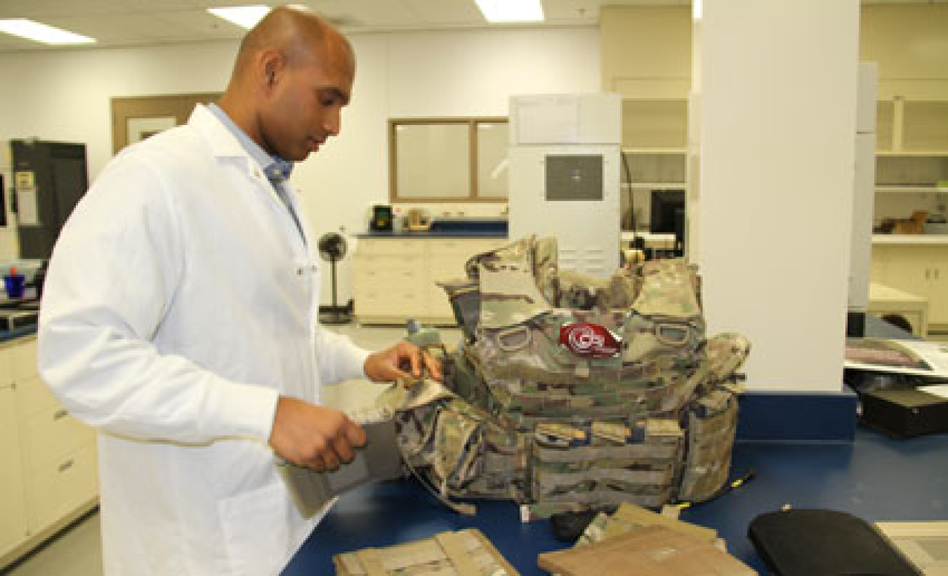 A researcher works on a machine as he develops light weight equipment for soldiers.