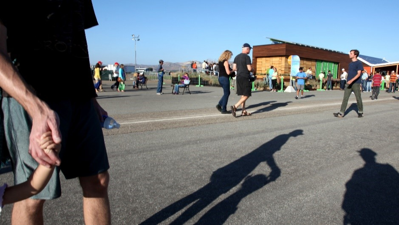 A crowd of people walk among solar powered houses.