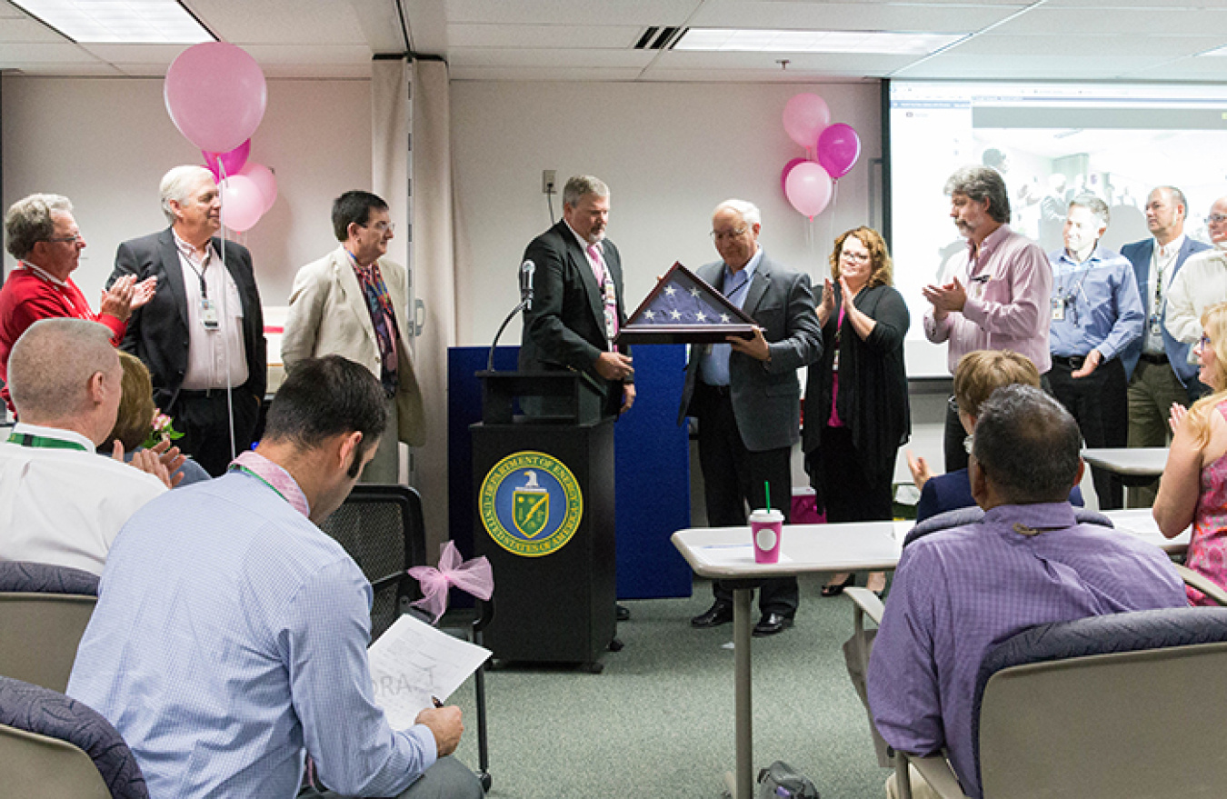 Ben Harp, Office of River Protection (ORP) Deputy Manager (center) and the rest of ORP senior leadership team present retiring ORP Manager Kevin Smith (center right) with the flag that flew over the ORP building during his tenure as ORP manager.