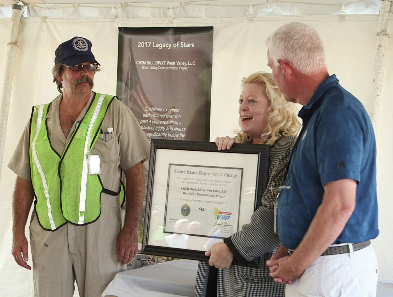 Stacy Charboneau, EM APDAS for Field Operations, presents a Voluntary Protection Program (VPP) recertification certificate and VPP flag to Rob Dallas, president of the International Association of Machinists and Aerospace Workers, Lodge 2401.