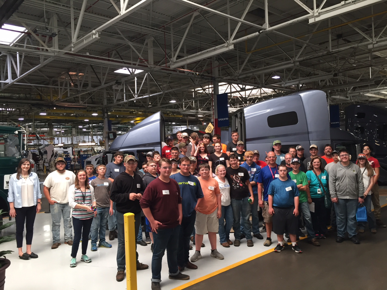 A group of students gather in front of a semi-truck cab inside the Volvo Trucks plant on Manufacturing Day 2017.