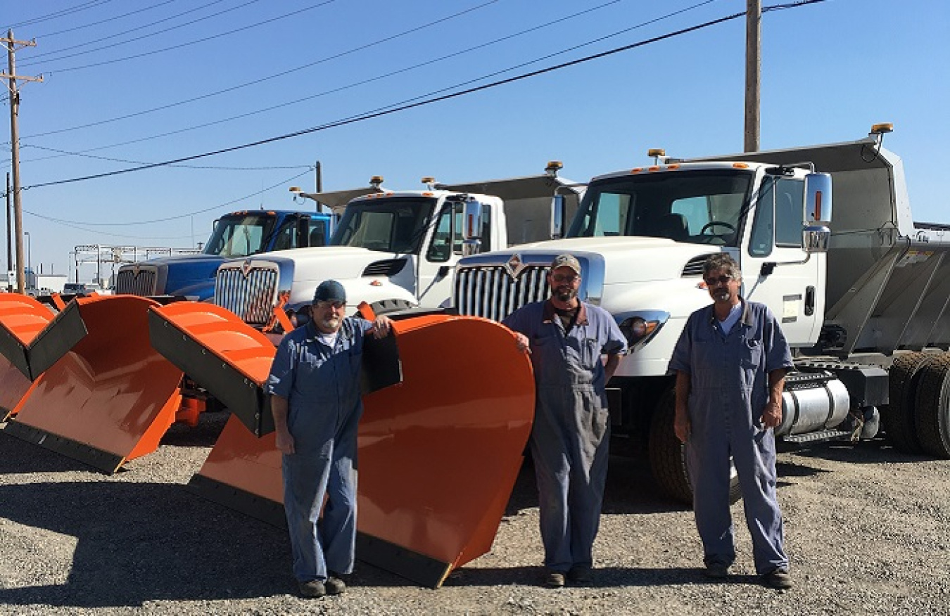 Mission Support Alliance Fleet Maintenance mechanics stand next to a new 3,000-pound snow plow.