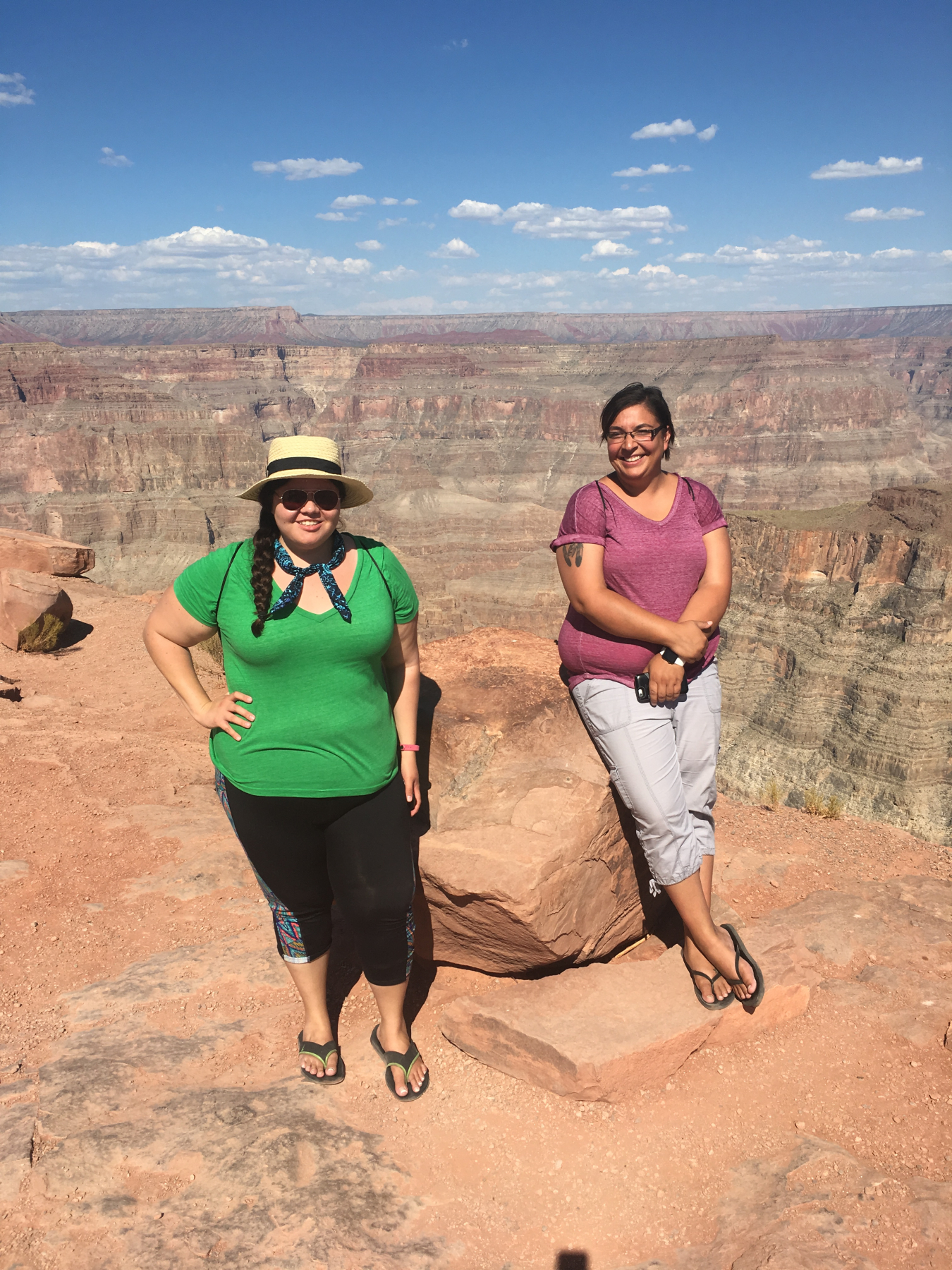 Two women stand in front of Grand Canyon.