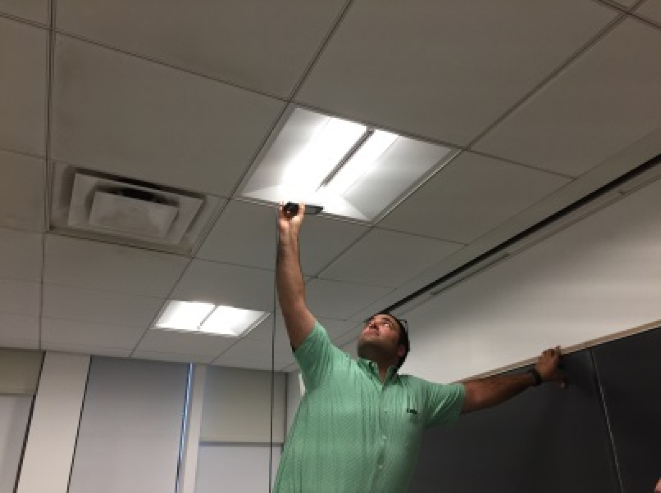 Photo of a man inspecting a light fixture.