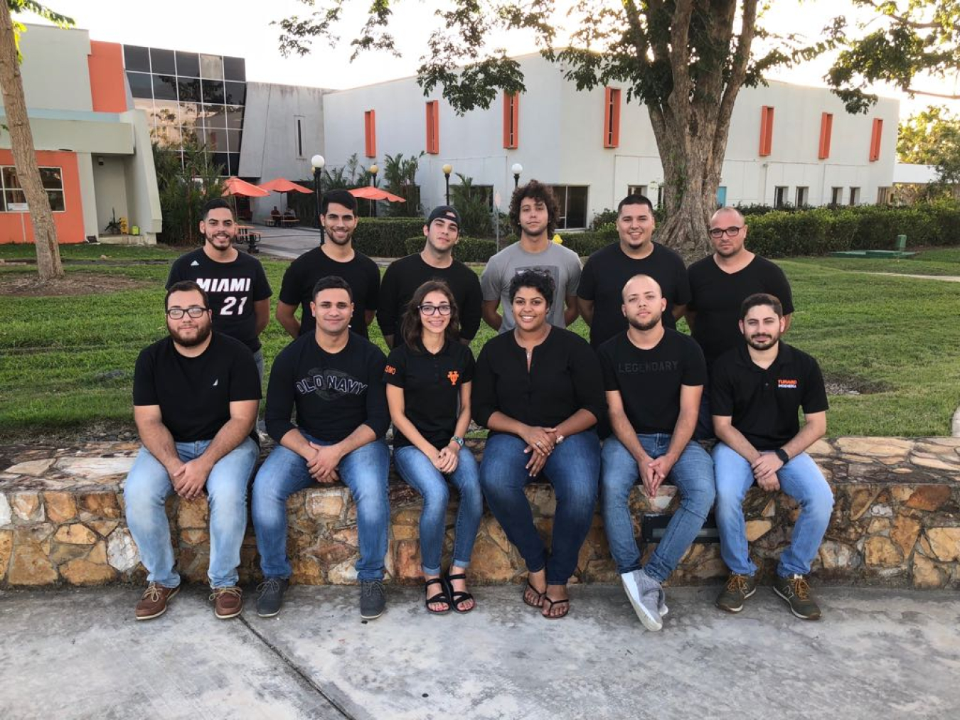 The Universidad del Turabo Collegiate Wind Competition 2018 team sits on a rock wall outside their university