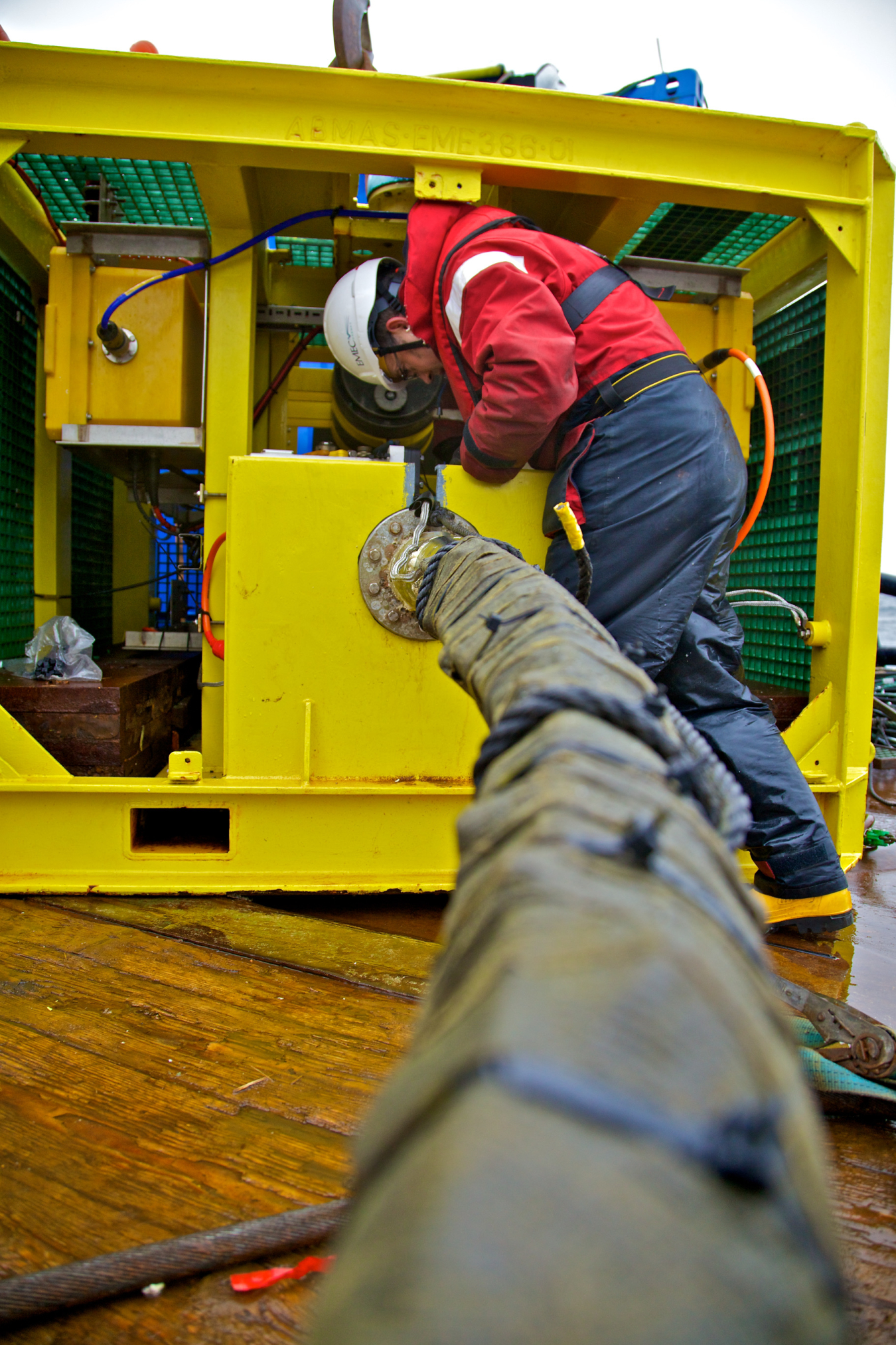 A man attaches a cable to a yellow monitoring pod.