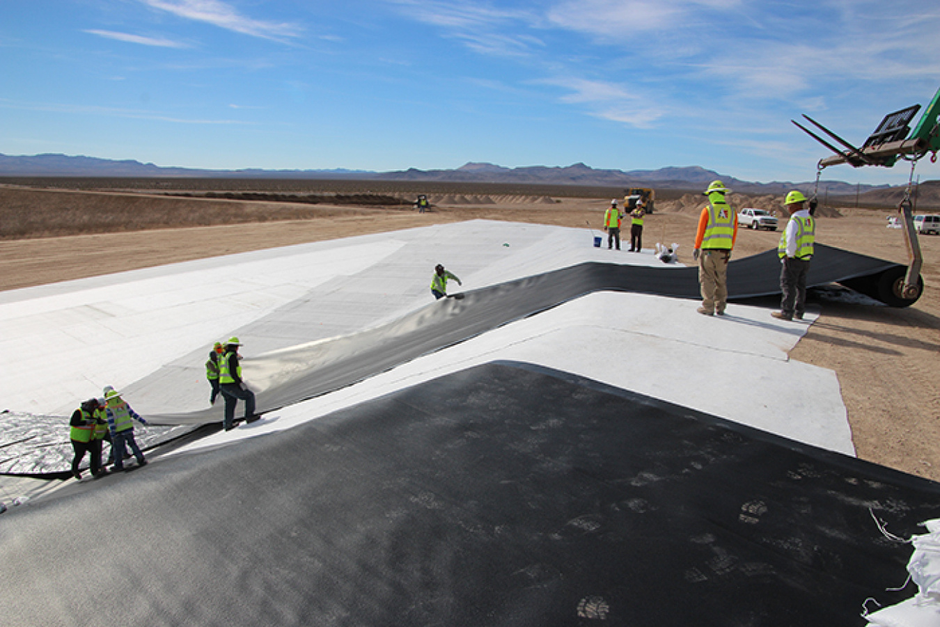Workers install the first of the two liners for the disposal cell.