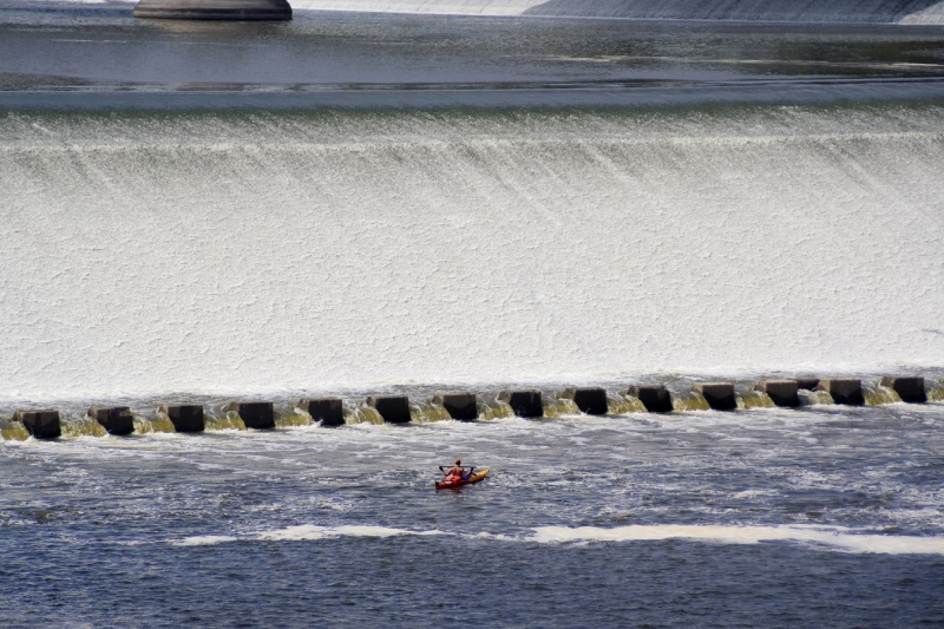 Photo of a kayaker in front of a dam.