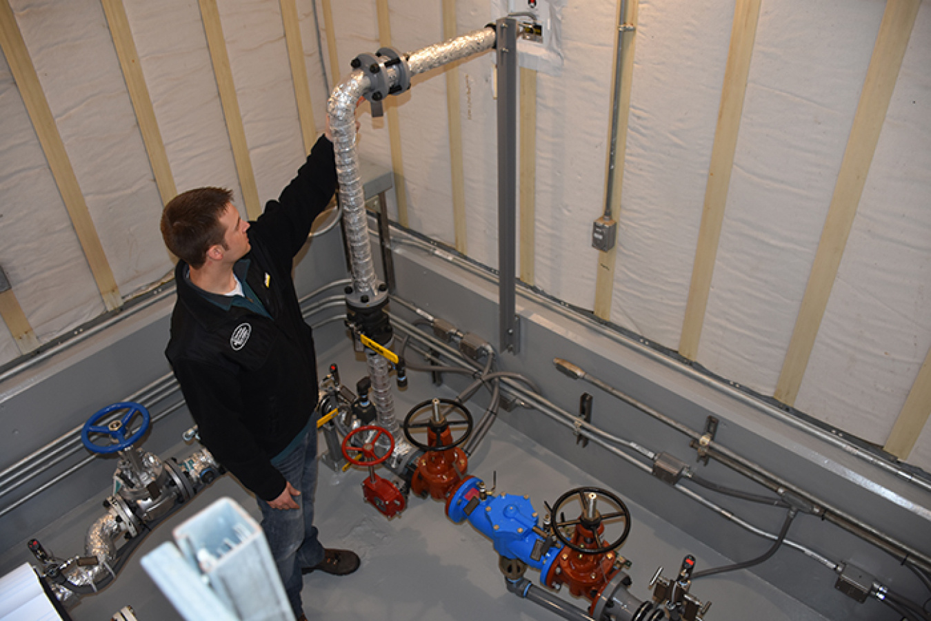 Washington River Protection Solutions engineer and project manager Dustin May points out a hookup for hot water in the refurbished AP-801 service water building.
