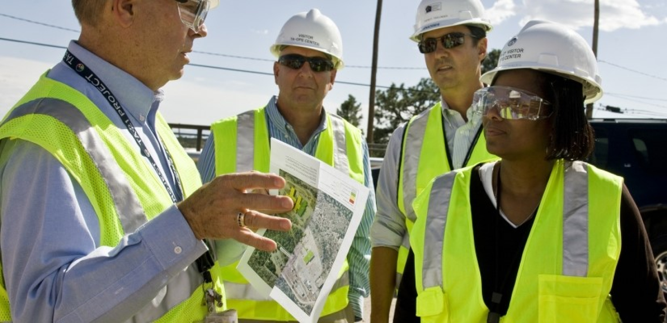 four people wearing reflective vests and hard hats.