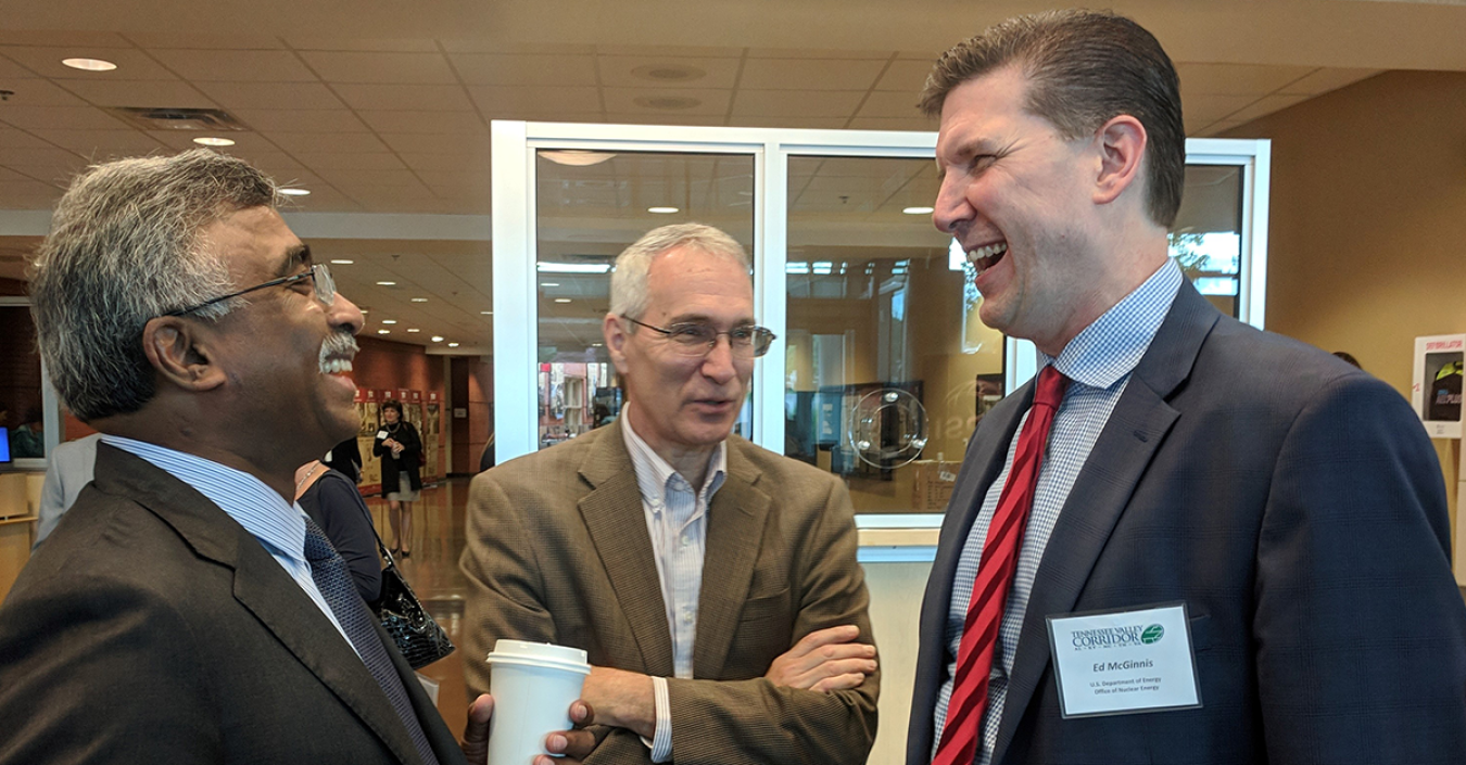 Three men in a group talking and laughing.
