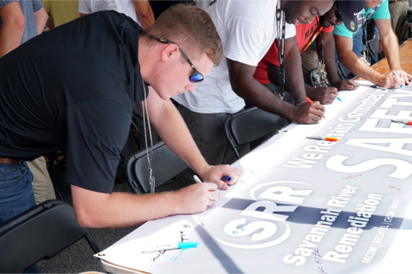Savannah River Remediation (SRR) employees sign banner as a commitment to safety.