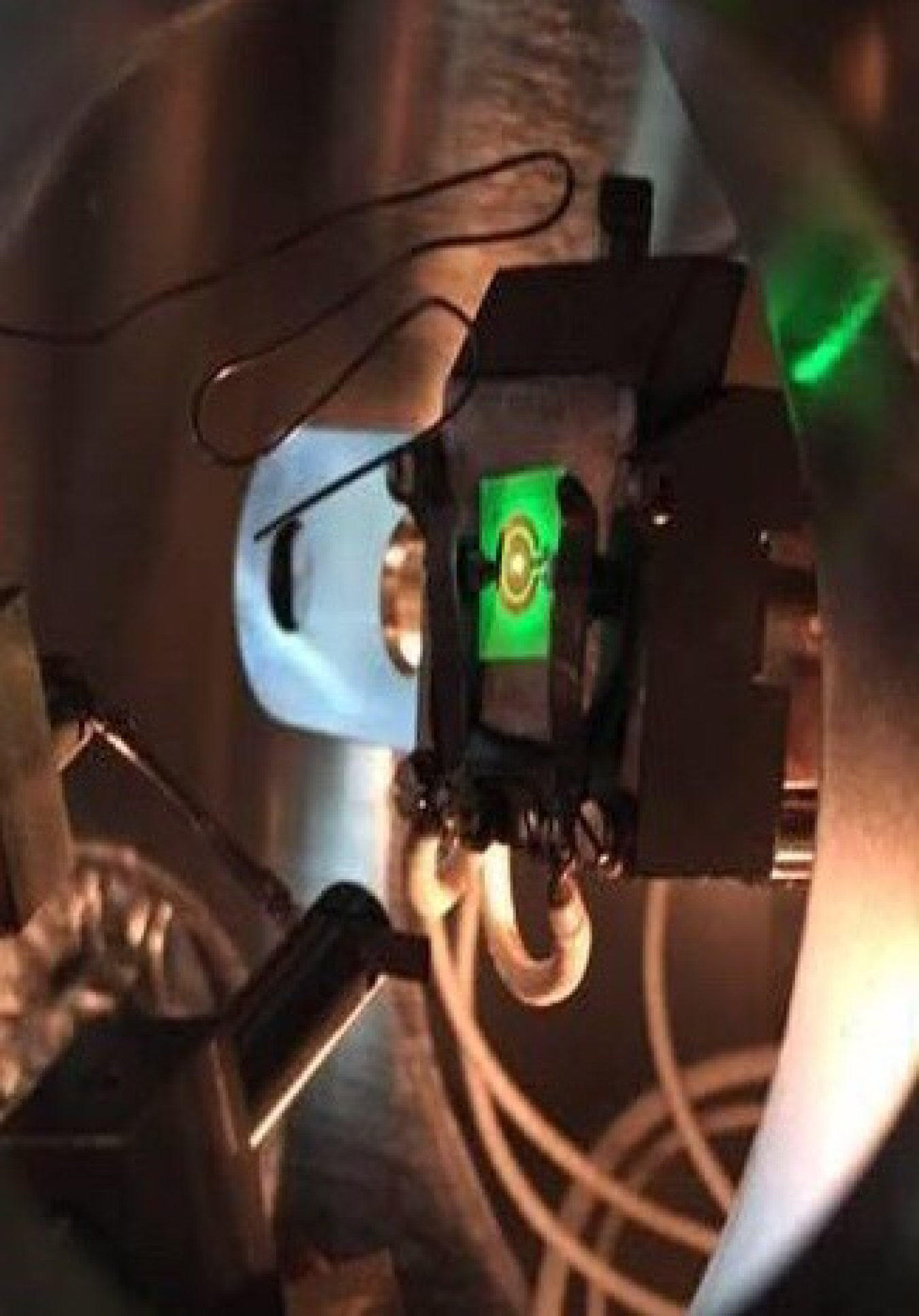 A green LED being electrically powered inside an ultra-high vacuum electron emission spectroscopy chamber.