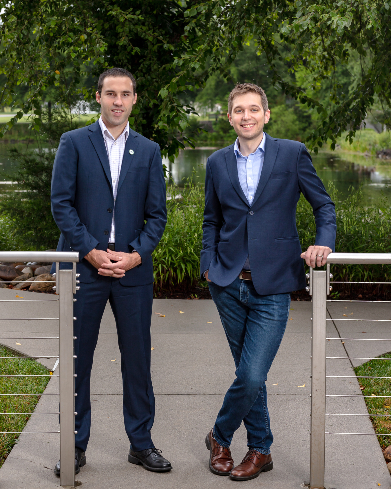 a photo of two men standing in front of a small lake.