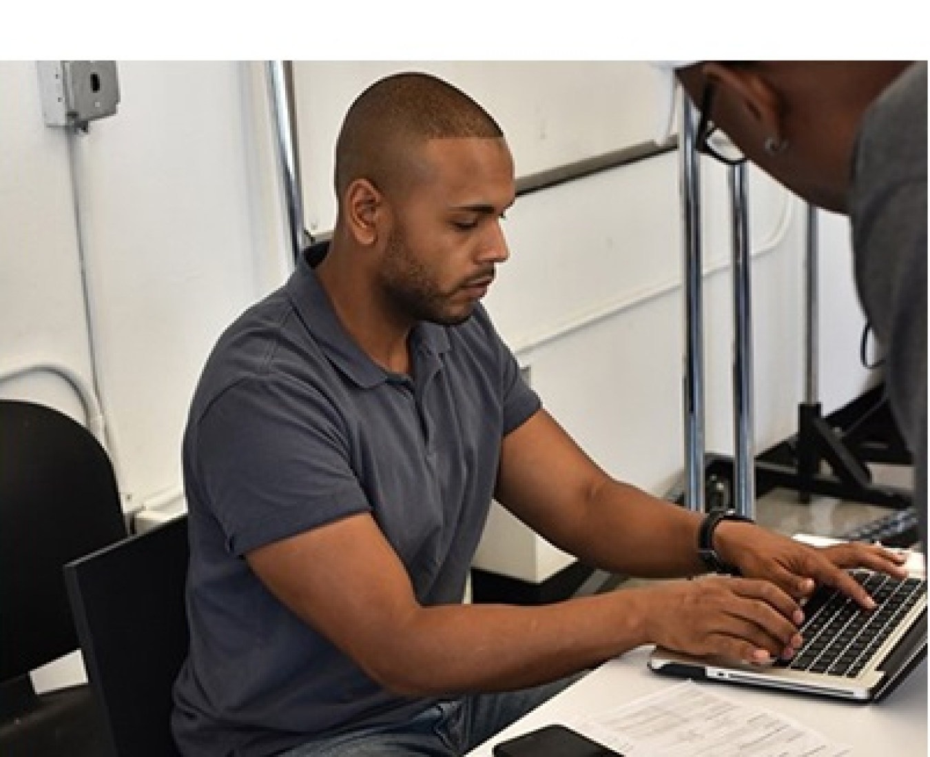 Photo of a man typing on a laptop computer. 