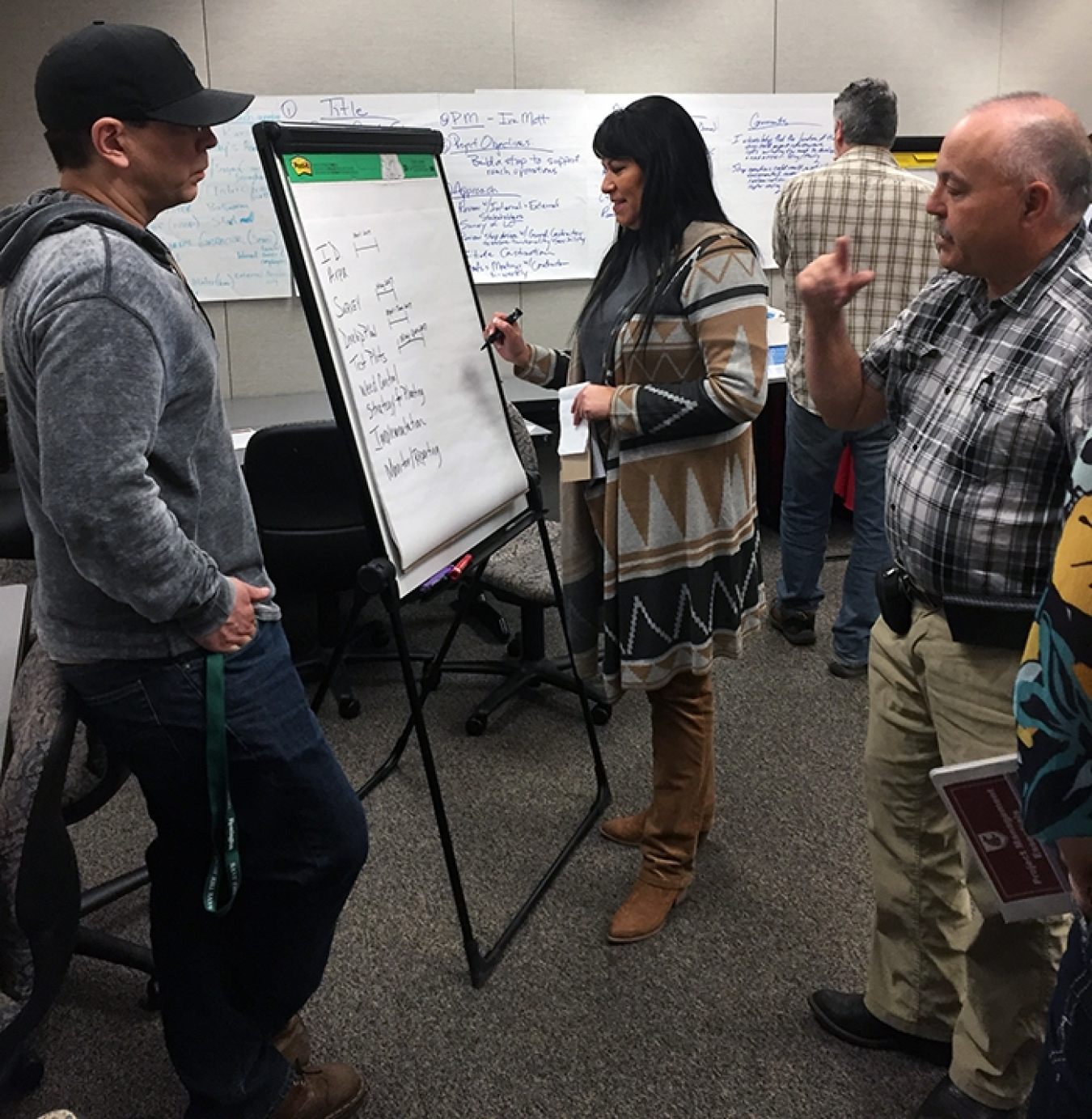 Mike Sobotta of the Nez Perce Tribe, left to right, Michelle Burke, an EM contractor, and Steve Link of the Confederated Tribes of the Umatilla Indian Reservation collaborate on a schedule for a mock tribal revegetation project.