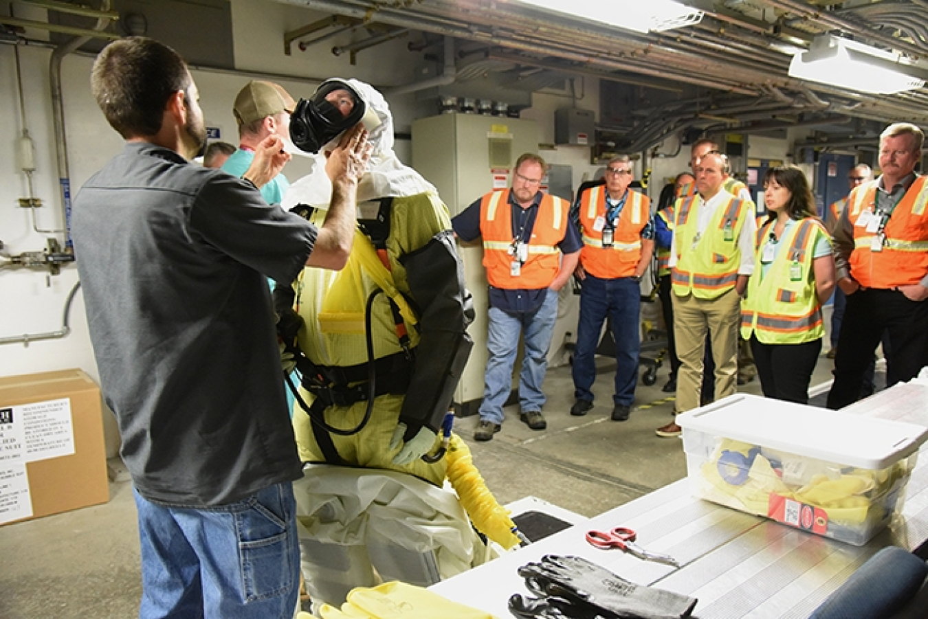 a. State and Tribal Government Working Group and National Governors Association Federal Facilities Task Force members view operations in the Transuranic Storage Area Retrieval Enclosure during their tour.