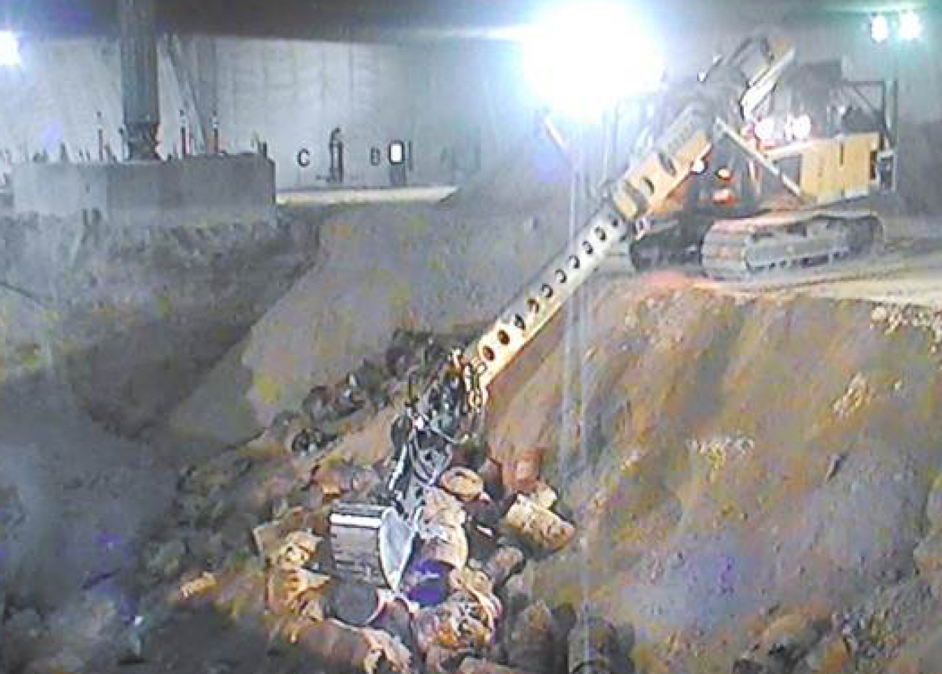 Crews use an excavator with an extended boom to exhume buried waste at the Accelerated Retrieval Project facilities at the Idaho National Laboratory Site.