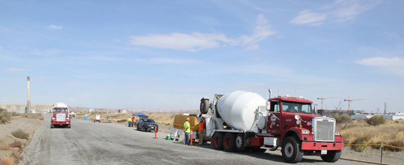 Trucks carry engineered grout from a nearby batch plant to the PUREX Plant Tunnel 2, where pumps insert the grout using piping connected to existing openings in the top of the tunnel.
