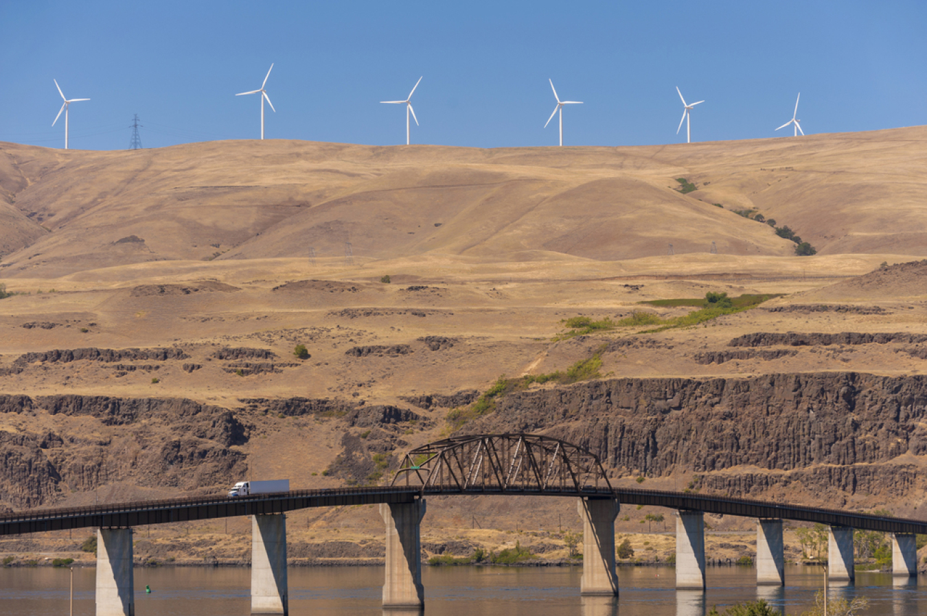 Photo of a series of wind turbines on top of a tall, earthen hill.