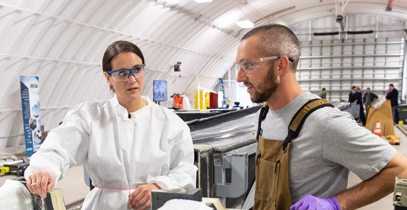 Two researchers work on a mold for a wind blade turbine.
