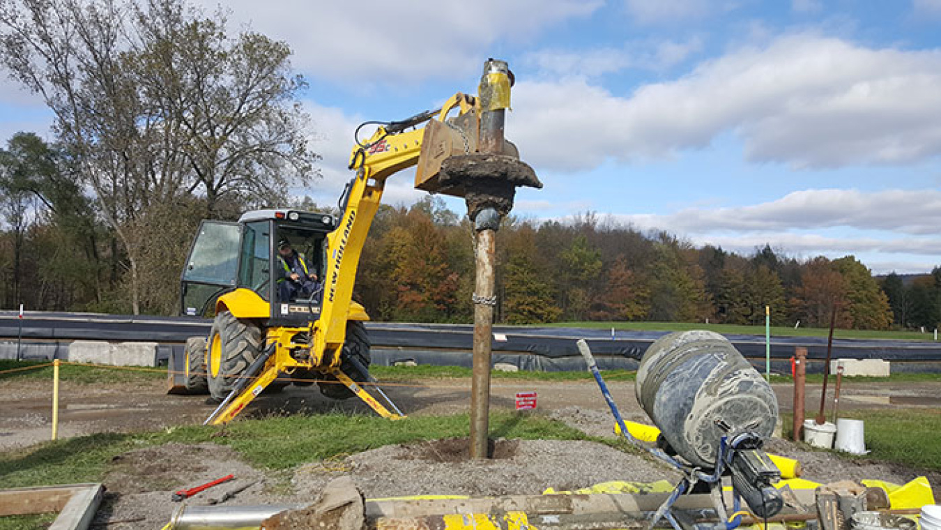 A backhoe is used to pull the well pump and casing from the ground after workers stabilized the casing with grout.