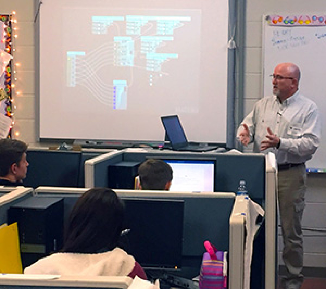 Oak Ridge Office of Environmental Management Graphic Specialist David Brown speaks to students in Hardin Valley Academy’s computer science classes. The screen behind him shows a sample of the coding he uses to create 3-D virtual models.