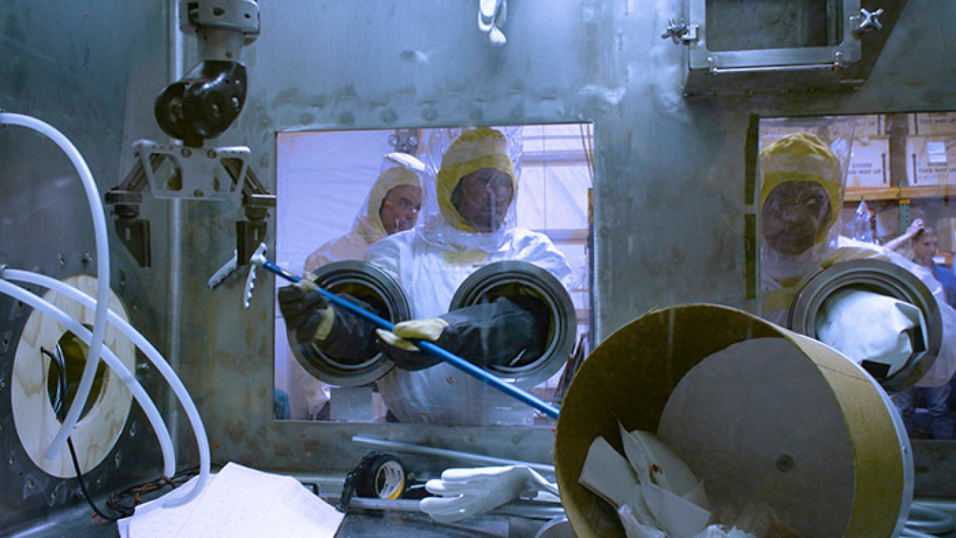 A 235-F risk reduction team operator works in a glovebox with specialized gloves to reduce the risk of radiation exposure.