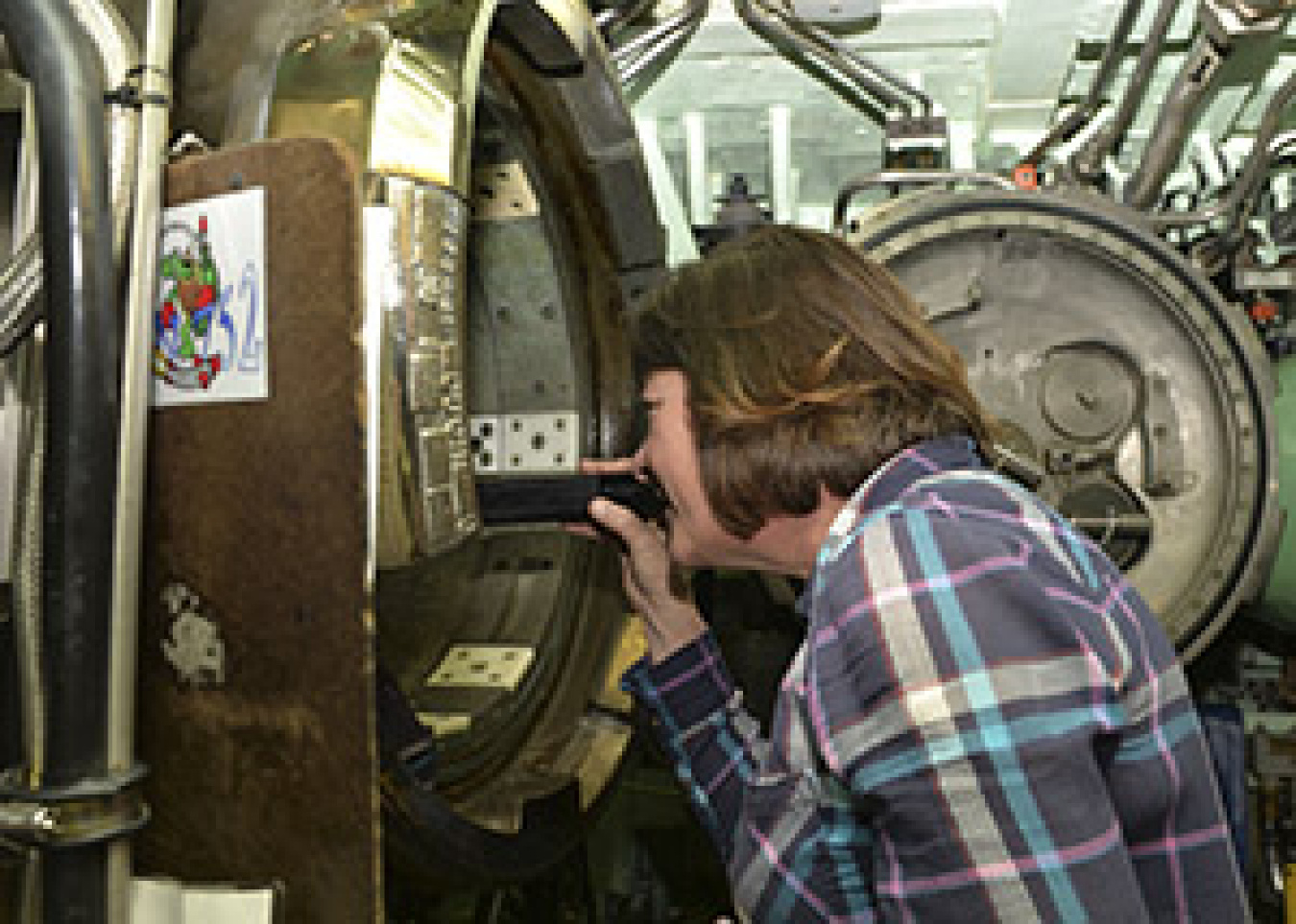 EM Assistant Secretary Anne White peers down an empty torpedo tube on the USS Pasadena.