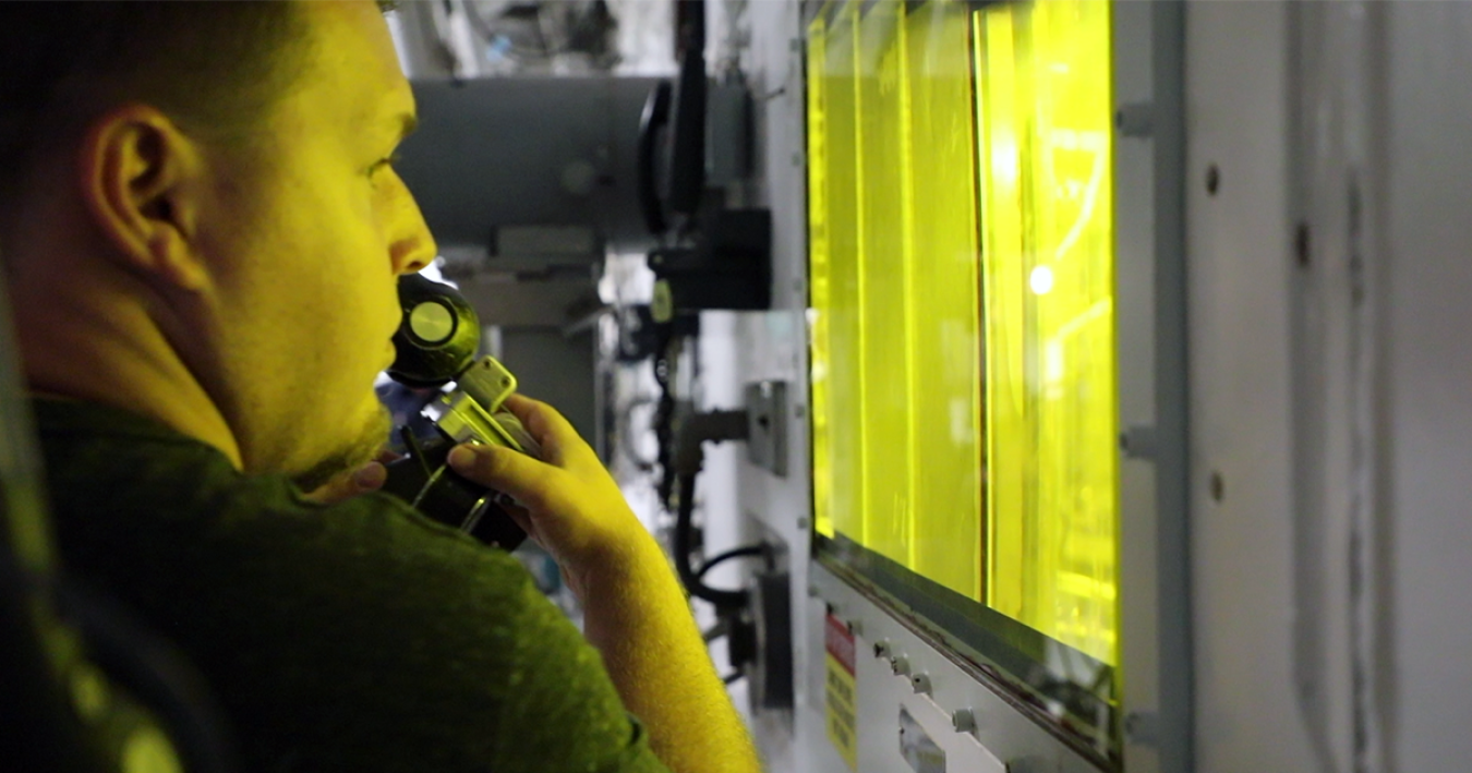 A researcher at ORNL works with a robotic arm outside of a hot cell.