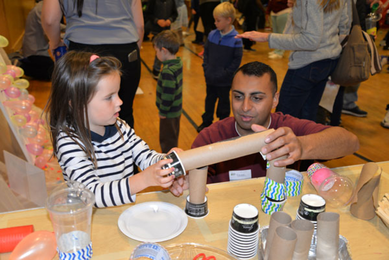 Sandia systems engineer Raheel Mahmood shows a student how to construct a roller coaster track for marbles.