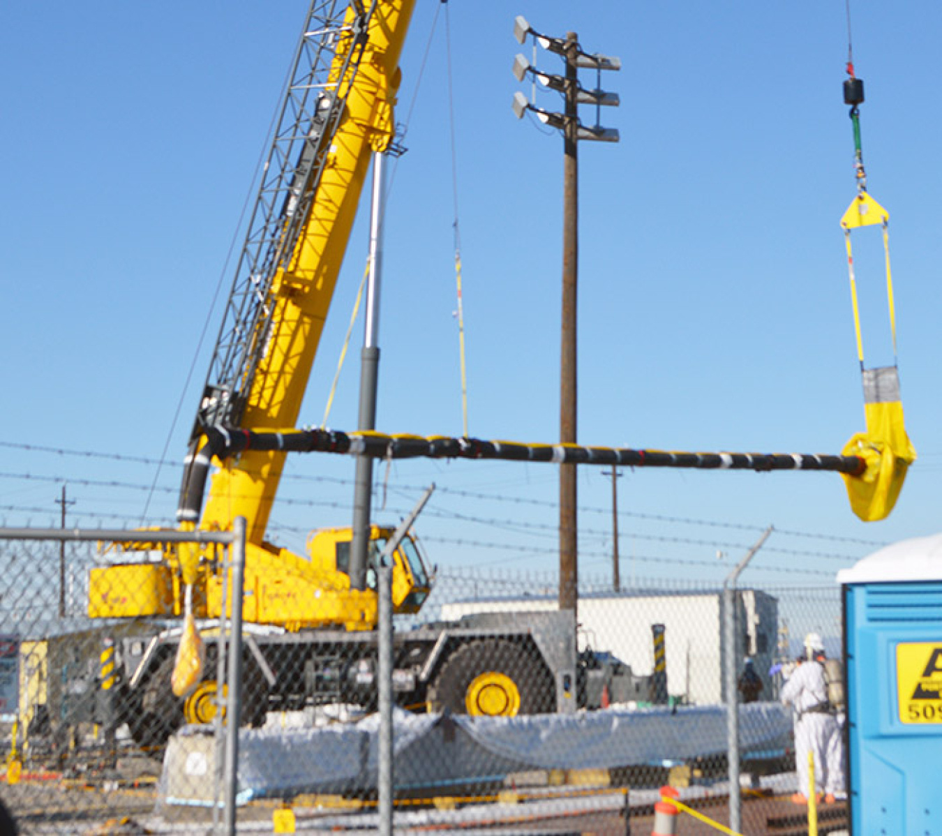 With help from a second crane, the outdated pump is lowered horizontally toward the disposal box.