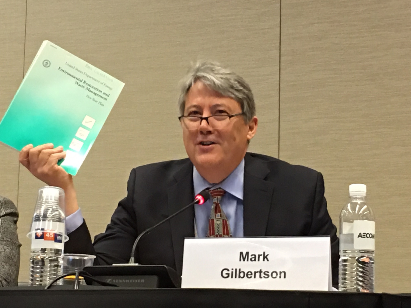 EM Principal Deputy Assistant Secretary Mark Gilbertson holds up the first Environmental Restoration and Waste Management Five Year Plan, a document from the earliest days of the Department of Energy cleanup program.