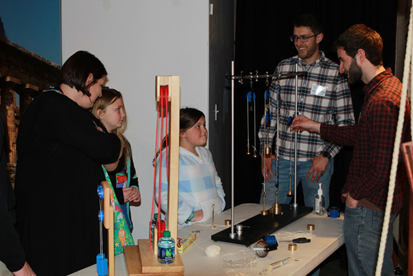 Fluor Idaho mechanical engineers Chris Graham and Derek Allen demonstrate how pulleys can provide a mechanical advantage to lifting heavy weights to, from left, Jennifer Redman and her daughters Emma and Abby.