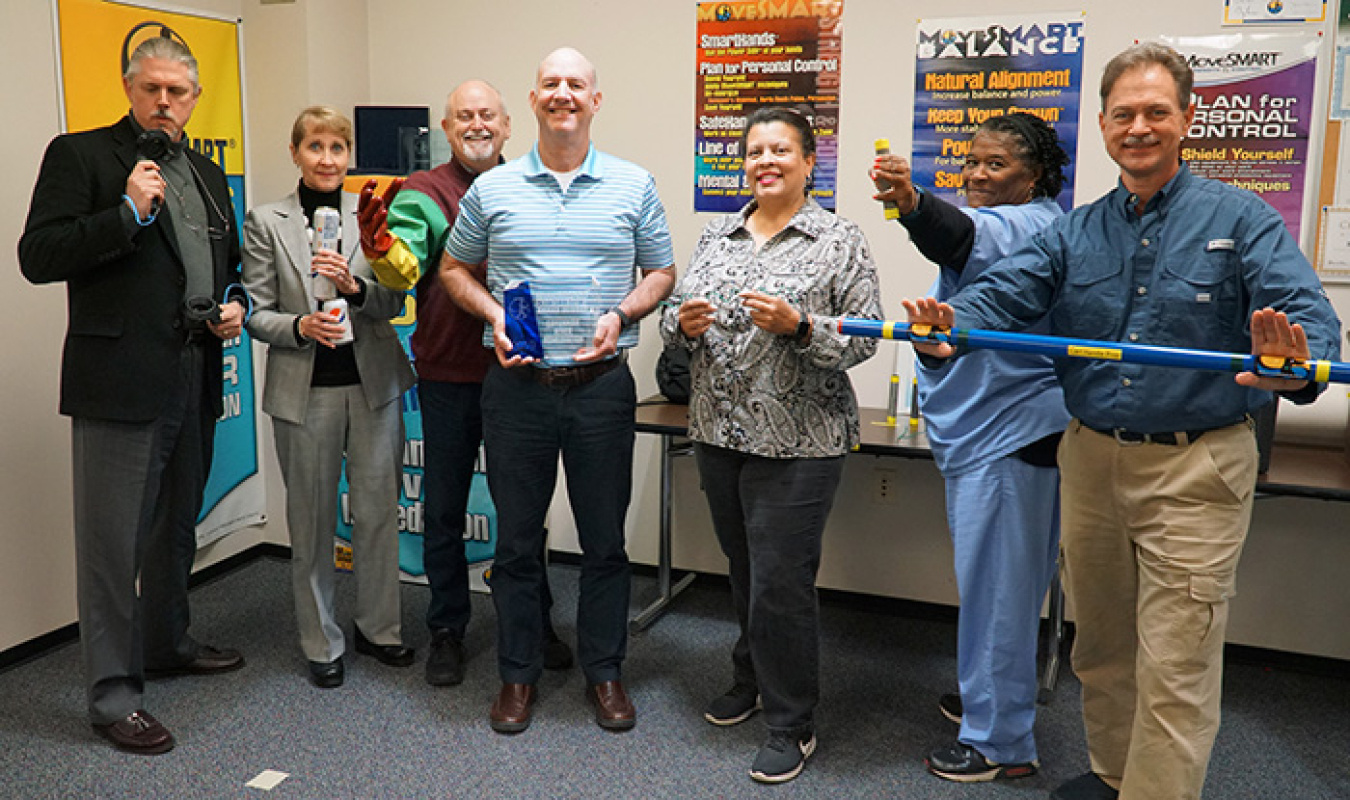 Savannah River Remediation (SRR) Environmental Safety and Health Programs Manager Kevin Smith, center, holds the 2019 MoveSMART Excellence Award given to SRR. Other SRR employees display MoveSMART props used during training classes. From left are Terry Mi