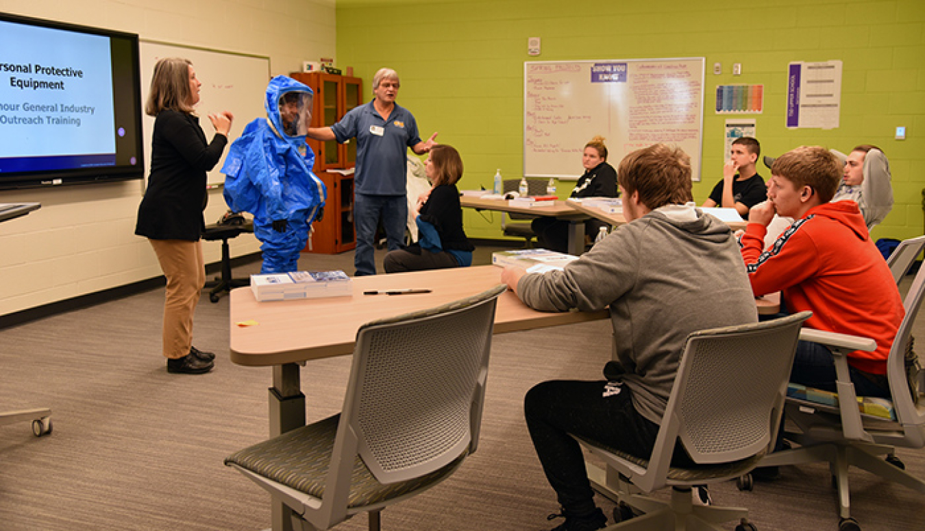 Instructor Billy Edington and an oral interpreter discuss how to don personal protective gear during the training.