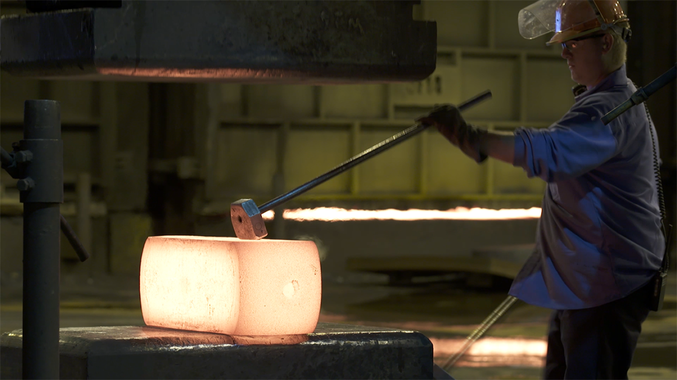 A worker forges metal at a manufacturing facility.