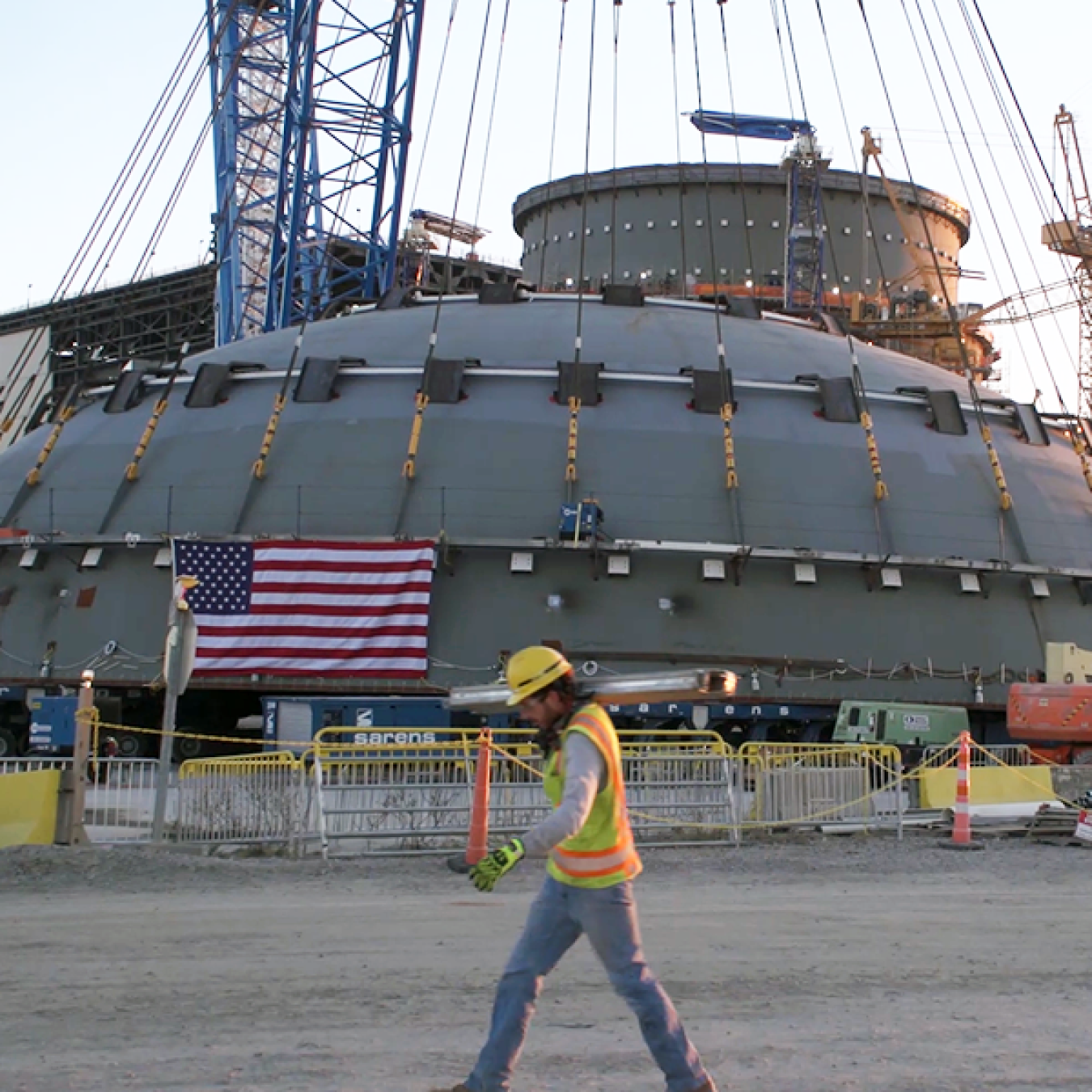 A photo of man walking by the top of a containment structure for a nuclear reactor